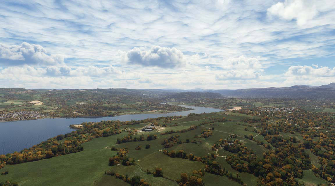 Scenic aerial view of lake surrounded by rolling hills, showcasing natural beauty and tranquility.