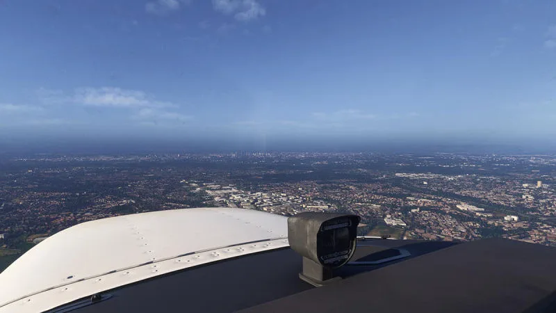 Aircraft nose view toward a distant city skyline on a clear day, REX Atmos CORE in Microsoft Flight Simulator 2024