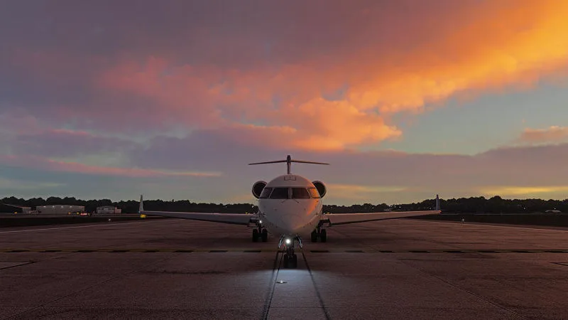 Bombardier CRJ regional jet on the apron beneath a pink-and-orange sunset sky, REX Atmos CORE in Microsoft Flight Simulator 2024