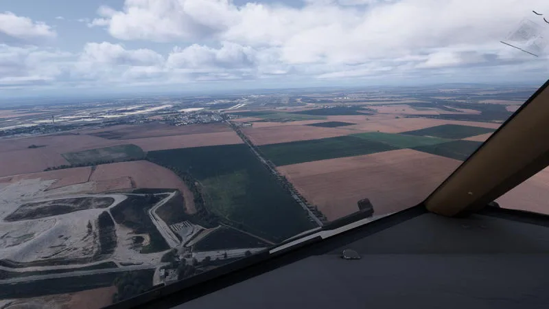 Wing view over patchwork farmland fields beneath scattered clouds, REX Atmos CORE in Microsoft Flight Simulator 2024